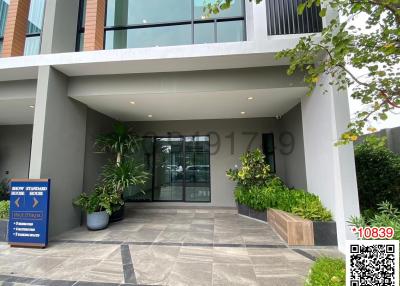 Modern apartment building entrance with large glass doors and landscaped pathway