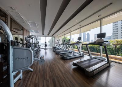 Modern gym with cardio equipment and floor-to-ceiling windows in an upscale apartment complex