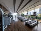 Modern gym with cardio equipment and floor-to-ceiling windows in an upscale apartment complex