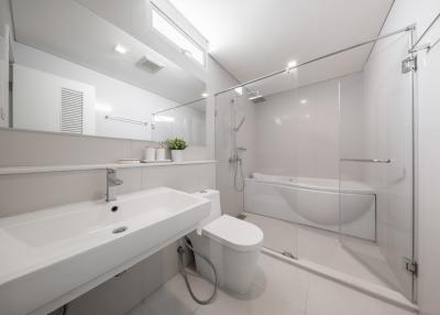 Modern white bathroom interior with glass shower enclosure, bathtub, and bright lighting