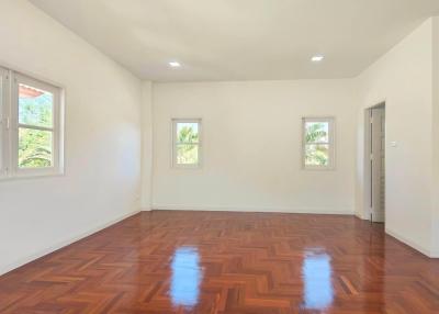 Spacious bedroom with polished hardwood floors and ample natural light