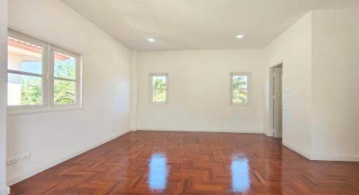 Spacious bedroom with polished hardwood floors and ample natural light