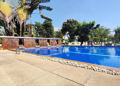 Spacious outdoor swimming pool with surrounding palm trees and seating area