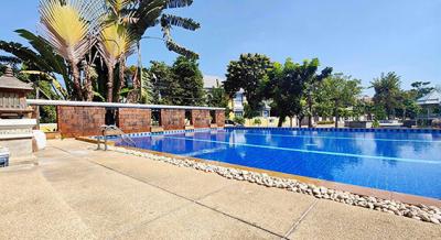 Spacious outdoor swimming pool with surrounding palm trees and seating area