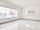 Empty spacious living room with large windows and glossy tiled floor