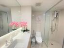 Modern bathroom with glass shower and vibrant pink flowers on the vanity