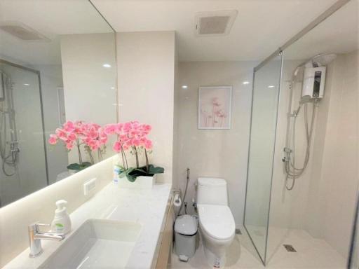 Modern bathroom with glass shower and vibrant pink flowers on the vanity