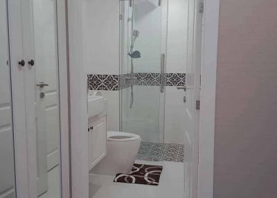 Modern white themed bathroom with glass shower and decorative floor tiles