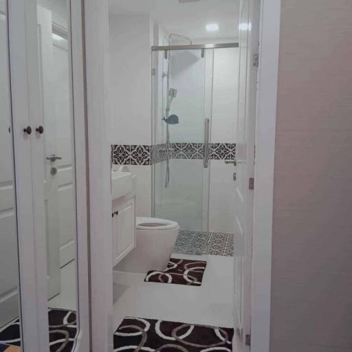 Modern white themed bathroom with glass shower and decorative floor tiles