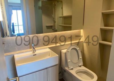 Modern bathroom interior with wall-mounted toilet, sink vanity unit, and built-in shelving