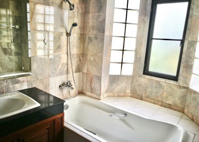 Spacious bathroom with marble tiles, bathtub, and separate shower area
