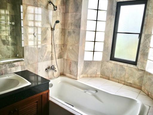 Spacious bathroom with marble tiles, bathtub, and separate shower area