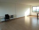 Spacious and well-lit empty living room with hardwood floors