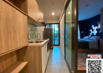 Modern apartment interior view showing kitchen leading to bedroom