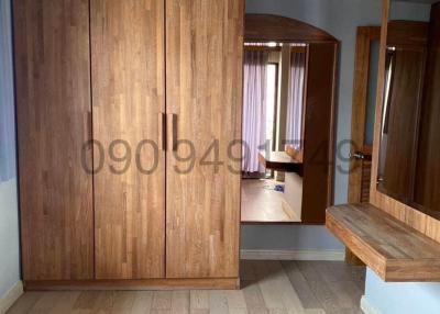 Spacious bedroom with wooden wardrobe and hardwood floors