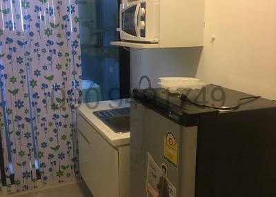 Compact kitchen space with modern appliances and floral curtain