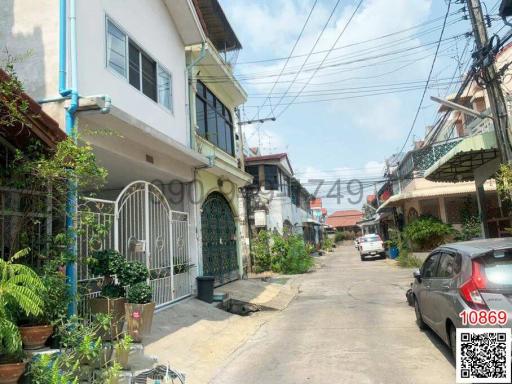 Street view of a residential building with gated entrance and greenery