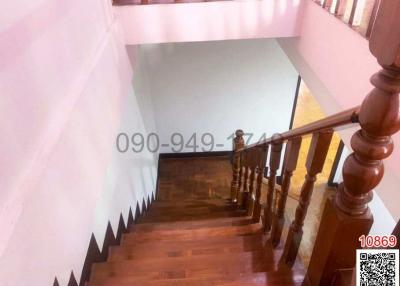 Wooden banister and steps in a well-lit staircase area
