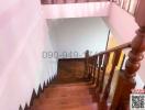 Wooden banister and steps in a well-lit staircase area