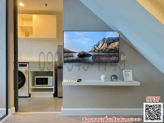 Modern living area with mounted television and adjacent kitchenette