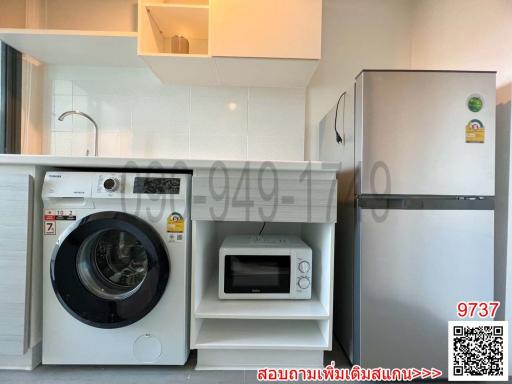 Modern kitchen with appliances including refrigerator, washing machine, and microwave