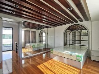 Spacious bedroom with mirrored closet doors and hardwood floors