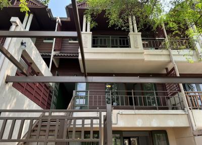 Exterior view of a multi-story residential building with balconies and lush greenery