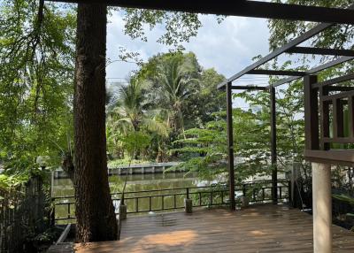 Spacious wooden deck with a serene view of lush greenery and a pond