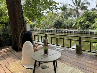 Person relaxing on riverside patio with greenery