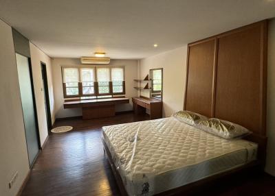 Spacious bedroom with large windows, hardwood floors, and built-in storage