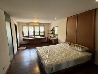 Spacious bedroom with large windows, hardwood floors, and built-in storage