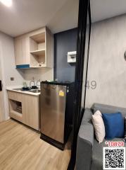 Compact combined kitchen and living area with modern appliances and cozy sofa