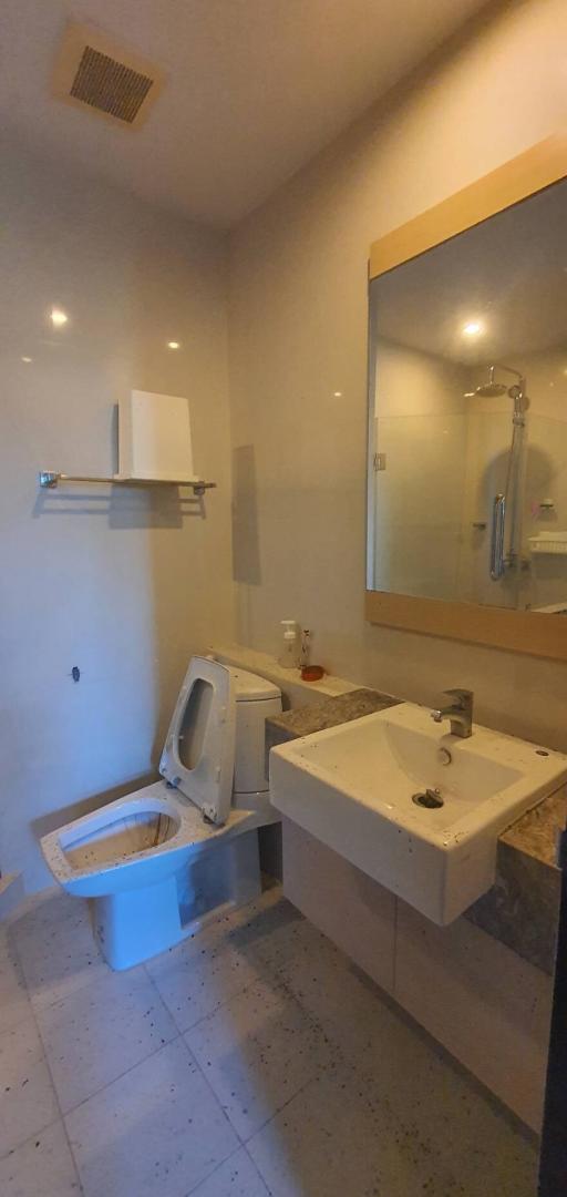 Modern bathroom with wall-mounted toilet, sink, and mirror