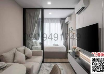 Modern bedroom with a view into the living room, furnished with large bed, wardrobe, and flat-screen TV