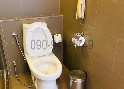 Modern bathroom with wall-mounted toilet, telephone and beige tiles