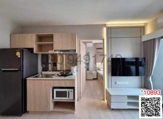 Modern kitchen with wooden cabinets and integrated appliances opening to a living space