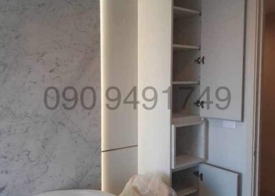 Modern bathroom with white marble walls, built-in shelving unit and round mirror