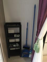 Corner of a room with cleaning supplies and a small shelf
