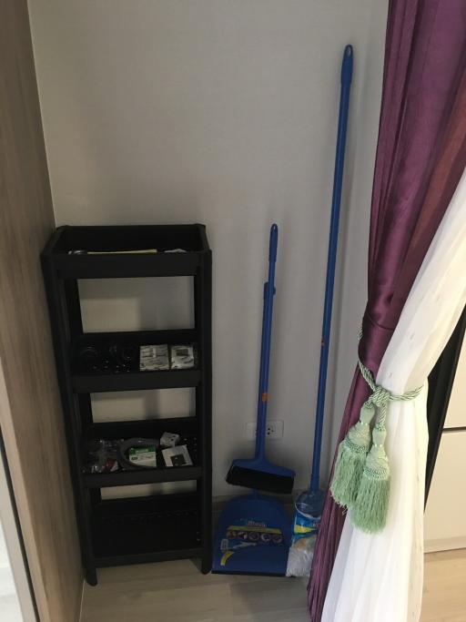 Corner of a room with cleaning supplies and a small shelf