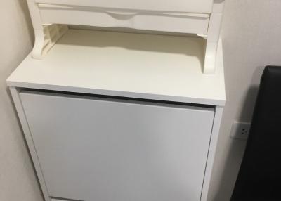 White wooden chest of drawers in a corner next to a black object
