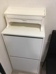 White wooden chest of drawers in a corner next to a black object