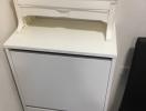 White wooden chest of drawers in a corner next to a black object