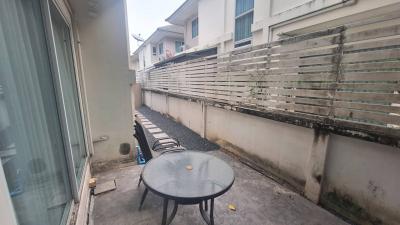 Small pebble-strewn outdoor patio area with a round table and metal fence