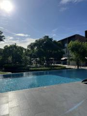 Swimming pool area in a residential complex with surrounding greenery