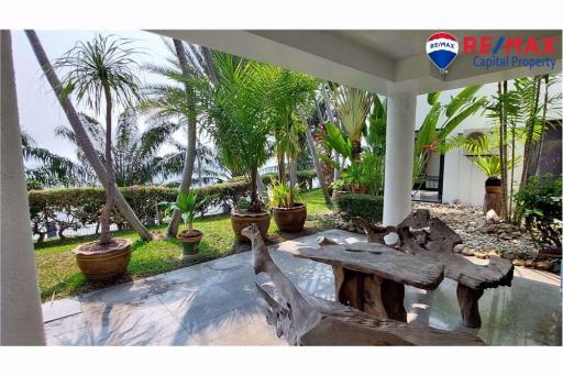 Spacious patio with garden view, tropical plants, and wooden furniture