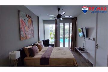 Modern bedroom with pool view, contemporary art, and mounted television