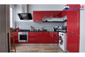 Modern kitchen with red cabinets, stainless steel appliances, and wood flooring