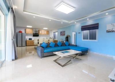 Spacious living room with modern open kitchen, bright blue accents and glossy floor tiles