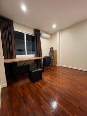 Modern bedroom with wooden flooring, desk area, and ample lighting