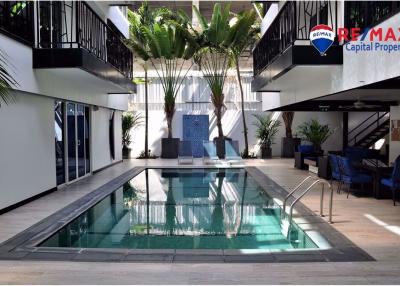 Indoor residential swimming pool with surrounding walkway and balcony
